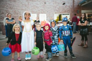 Little kids dressed in Halloween costumes.